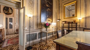 En elegant spisesal med et glasbord, detaljerede vægdekorationer og et stort spejl.