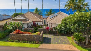 Une propriété située en bord de mer, dotée de panneaux solaires, d’un mur de soutènement en pierre et d’un jardin bien entretenu.