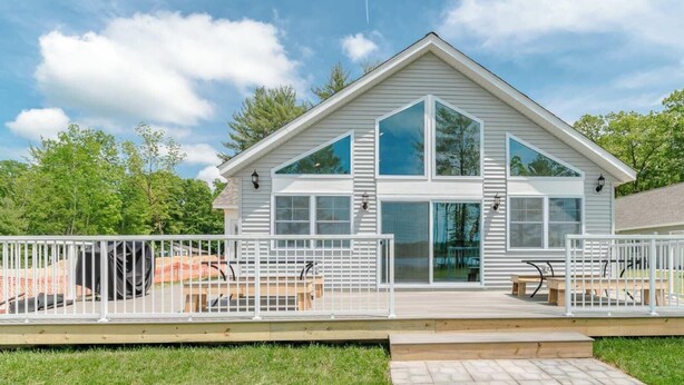 Ett hus i två våningar med en veranda, stora fönster och en inhägnad uteplats.