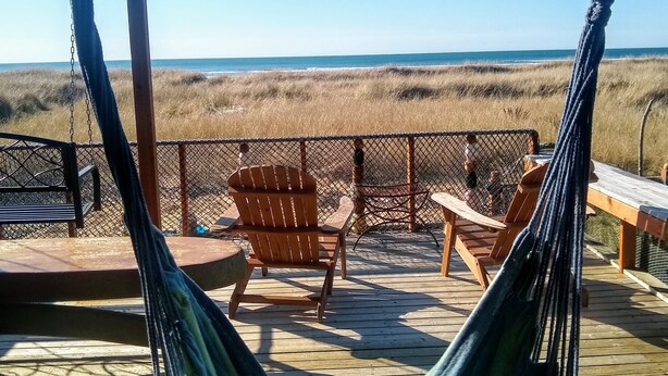 Eine Hängematte auf einer Holzterrasse mit Blick auf einen Strand.
