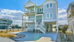 A multi-story residential building with a balcony, a staircase, and a garage. - 5547- Sailfish Station - Nags Head Luxury Home Private Pool OBX (Nags Head)