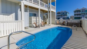 A swimming pool with a metal ladder, surrounded by white railings and wooden deck chairs. - 5547- Sailfish Station - Nags Head Luxury Home Private Pool OBX (Nags Head)