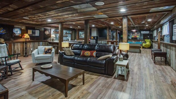 Un amplio salón con un sofá de cuero, sillones y una mesa de billar.
