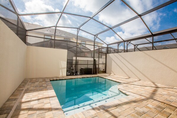 Une piscine dotée d’un toit en verre, entourée d’un sol en briques, et offrant une vue dégagée sur le ciel.