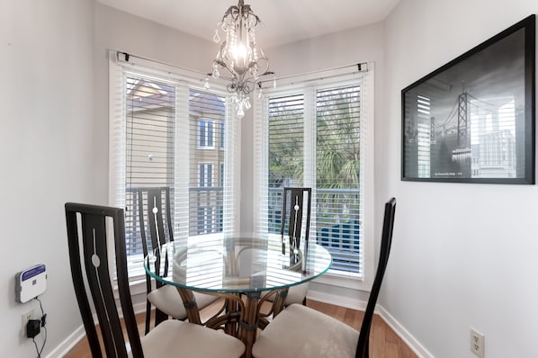 A dining area with a glass table, black chairs, and a chandelier.