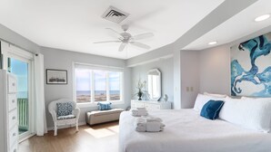 A bedroom with a large bed, a ceiling fan, a window with a view, a dresser, and a chair. - Direct Oceanfront w/ Views! Pool Access, screened porch - 202B Port O Call (Isle of Palms)
