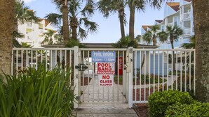 A gated entrance with a sign indicating pool hours and a band requirement.