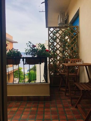 A balcony with a view of the sea, a wooden table, and chairs. - B&B Paradiso Relais (Messina)