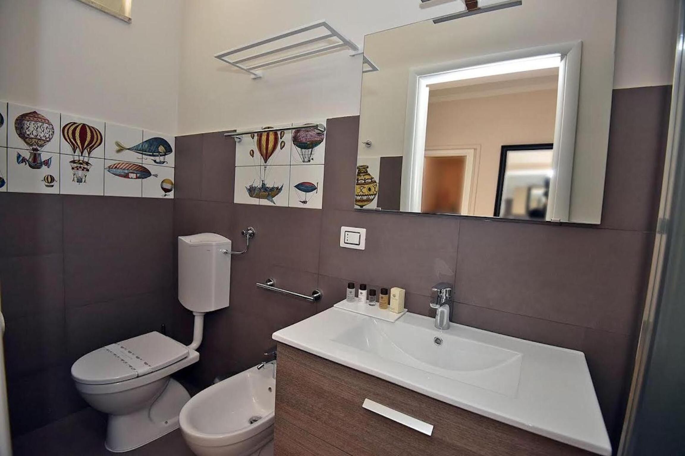 Un baño moderno con inodoro, bidé y un lavabo grande con espejo.