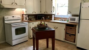 Une cuisine avec des meubles blancs, une cuisinière, un four à micro-ondes et un évier.