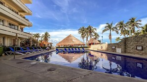 A pool area with blue lounge chairs, a thatched-roof structure, and palm trees. - Beautiful Ground Floor 2 BR Suite at Ixchel (Isla Mujeres)