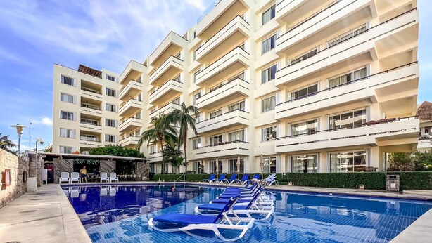 A hotel with a swimming pool, lounge chairs, and a palm tree. - Beautiful Ground Floor 2 BR Suite at Ixchel (Isla Mujeres)