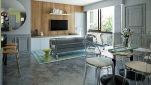 A modern kitchen with a wooden accent wall, a flat-screen TV, and a dining area with clear chairs and a glass table. - Singular Joy Downtown Residences (Playa del Carmen)
