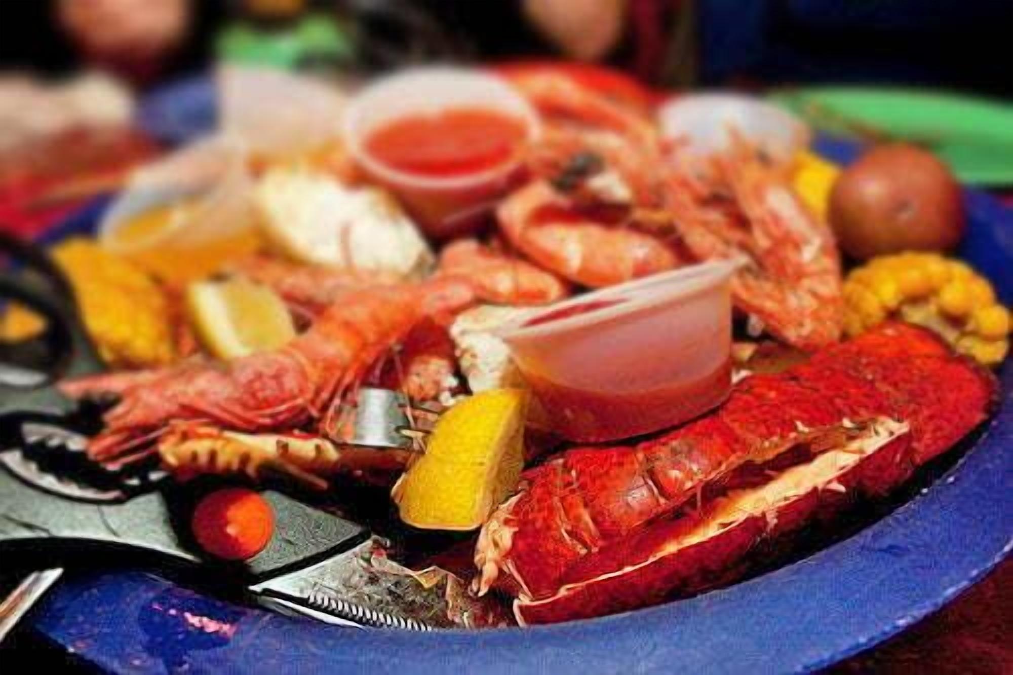 A seafood platter with various types of seafood, including shrimp and lobster, accompanied by lemon wedges and a small bowl of sauce.