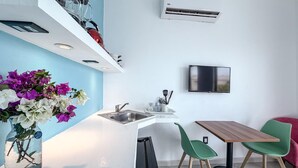 A modern kitchen with a built-in air conditioner, a sink, and a dining area with a table and chairs. - Just steps from downtown with balcony (Isla Mujeres)