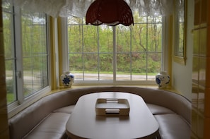 Enjoy a serene view of the lush landscape from the bay window, accompanied by a comfortable seating area with a curved bench and decorative vases.