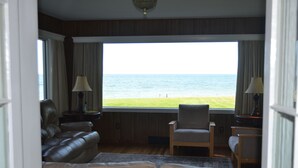 A room with a view of the sea, a leather sofa, a chair, and a lamp. - GREAT GETAWAY ! a 3200 sq. ft. LAKEFRONT HOUSE, LARGE YARD 176ft. OF WATERFRONT (Geneva)
