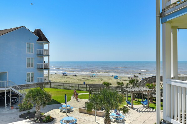 A beachfront hotel with a pool area, outdoor seating, and a view of the beach and ocean.