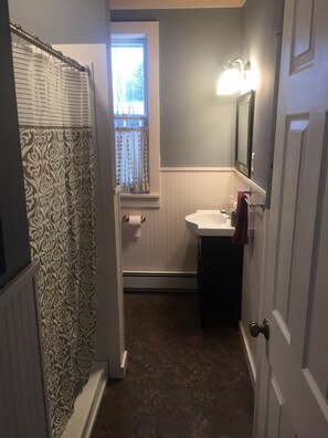 Une salle de bain avec un rideau de douche, une fenêtre donnant sur un beau paysage, un lavabo et un miroir.
