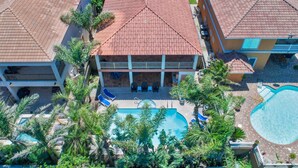 Un hôtel avec un toit recouvert de tuiles rouges, une piscine et un patio abrité.