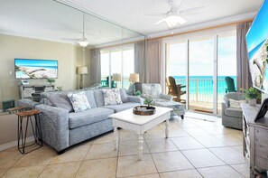 A living room with a sofa, coffee table, and a television displaying a beach scene.