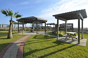 Un parque con un quiosco, mesas de picnic y una palmera.