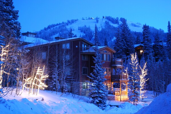 A multi-story building with a ski lift in the background, surrounded by snow-covered trees and a snowy landscape.