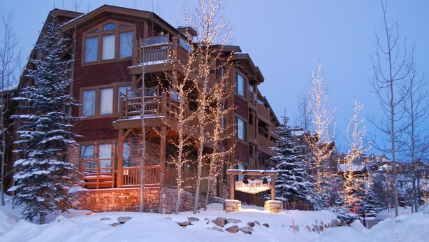 Een meerlaags landhuis met een stenen gevel, houten balkons en een bord met de tekst 'Black Bear Lodge'.