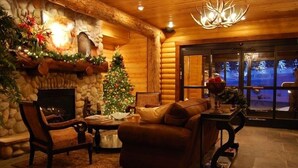 Een gezellig blokhutinterieur met een open haard, een kerstboom en een stenen muur.