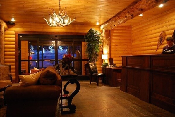 A cozy log cabin interior with a fireplace, leather furniture, and a large window overlooking a snowy landscape. - Cozy Silver Lake 2BR steps from lifts, dining, shops. Hot Tub, Pool, BBQ, WiFi (Park City , Black Bear Lodge)