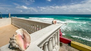 A balcony with a view of the ocean, featuring a railing and a seashell.