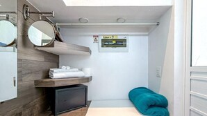 A compact bathroom with a mirror, towel rack, shelf, and a small heater. - 1BR with balcony (Isla Mujeres)