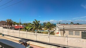 A balcony with a view of a swimming pool, palm trees, and buildings. - 1BR with balcony (Isla Mujeres)