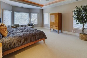 A bedroom with a large bed, a wardrobe, a chair, and a potted plant.