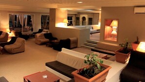 En hotellobby med soffor, fåtöljer, ett soffbord och krukväxter.