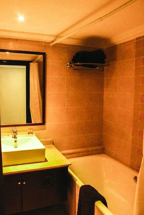 A bathroom with a sink, mirror, and bathtub.