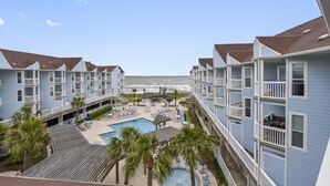 A hotel with a pool, beach view, and multiple balconies.