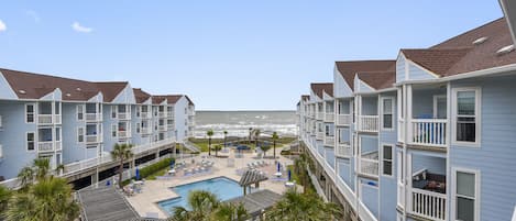 A hotel with a pool, beach view, and multiple balconies.