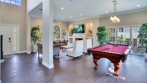 A spacious living room with a pool table, comfortable seating, a fireplace, and large windows offering views of the outdoors. - ☆ Tampa Riverfront Villa ☆ Heated Pool / Hot Tub / Kayaks / Pool Table (Tampa)