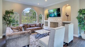 A spacious living room with a fireplace, comfortable seating, large windows, and a television. - ☆ Tampa Riverfront Villa ☆ Heated Pool / Hot Tub / Kayaks / Pool Table (Tampa)