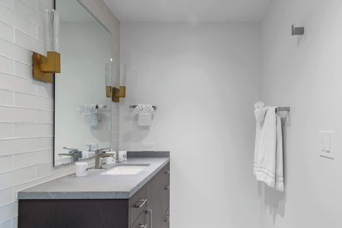 Een moderne badkamer met twee wasbakken, een grote spiegel en een handdoekhouder.