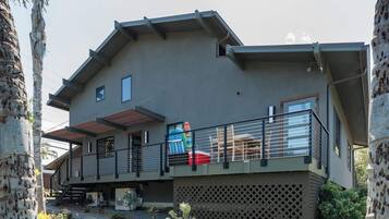 A modern two-story house with a balcony, a covered outdoor area, and a stone pillar.
