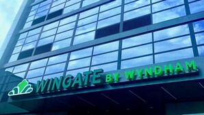 Een modern gebouw met een grote glazen gevel en een bord waarop 'Wingate by Wyndham' staat.