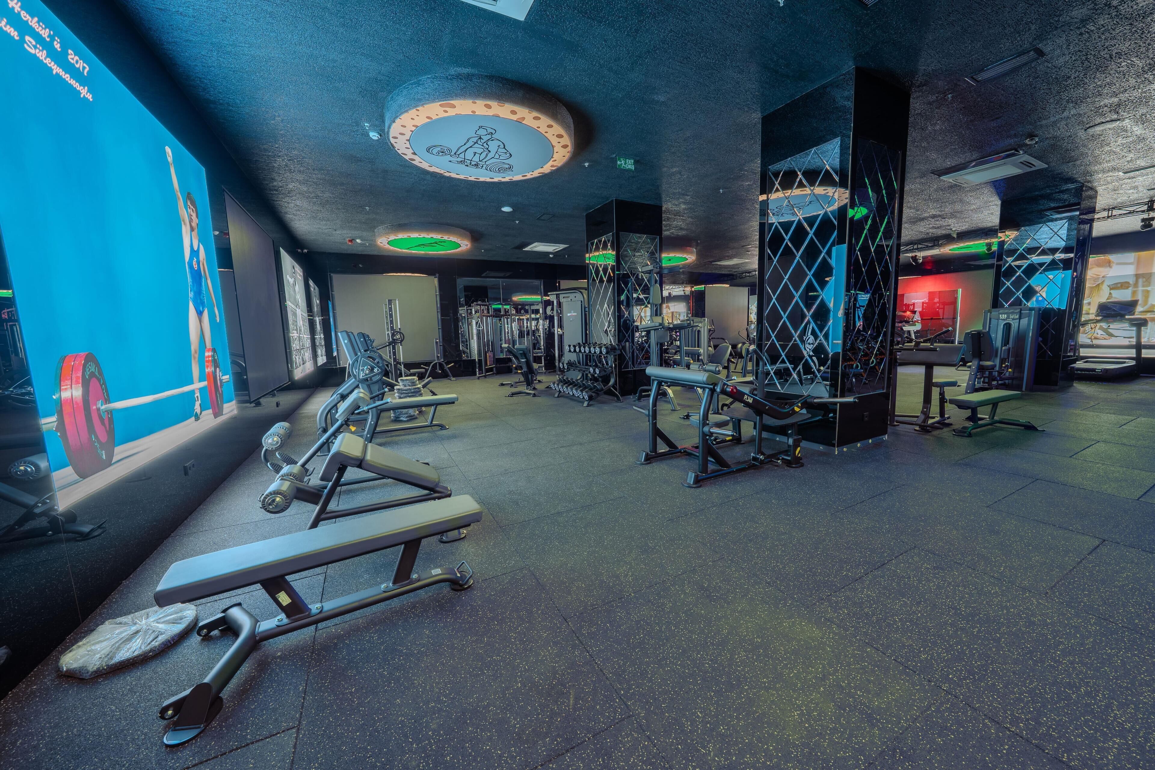 Un gimnasio con diversos equipos de ejercicio, incluyendo cintas de correr y máquinas de pesas.