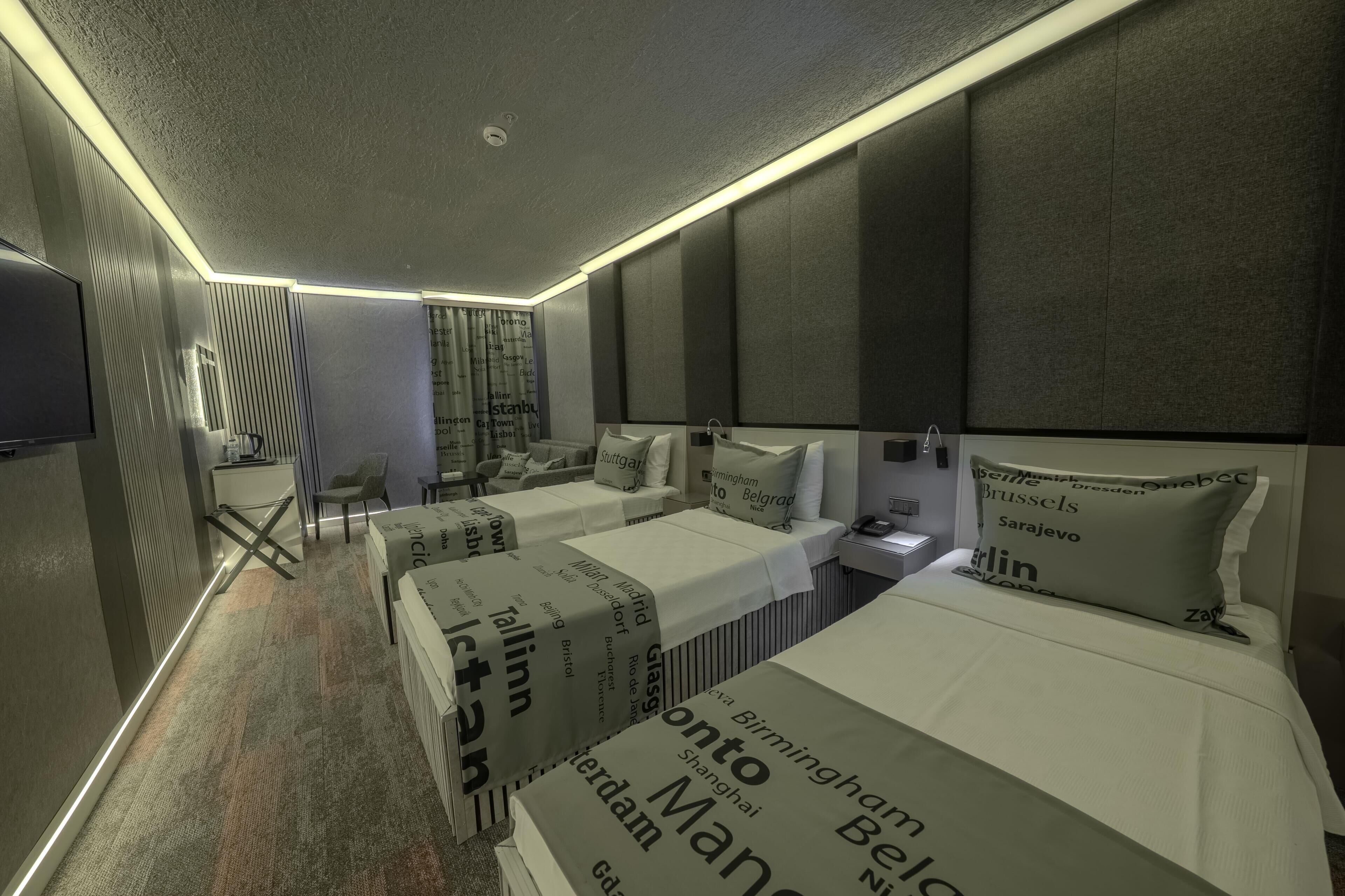 A hotel room with two beds, a desk, a chair, and a television.
