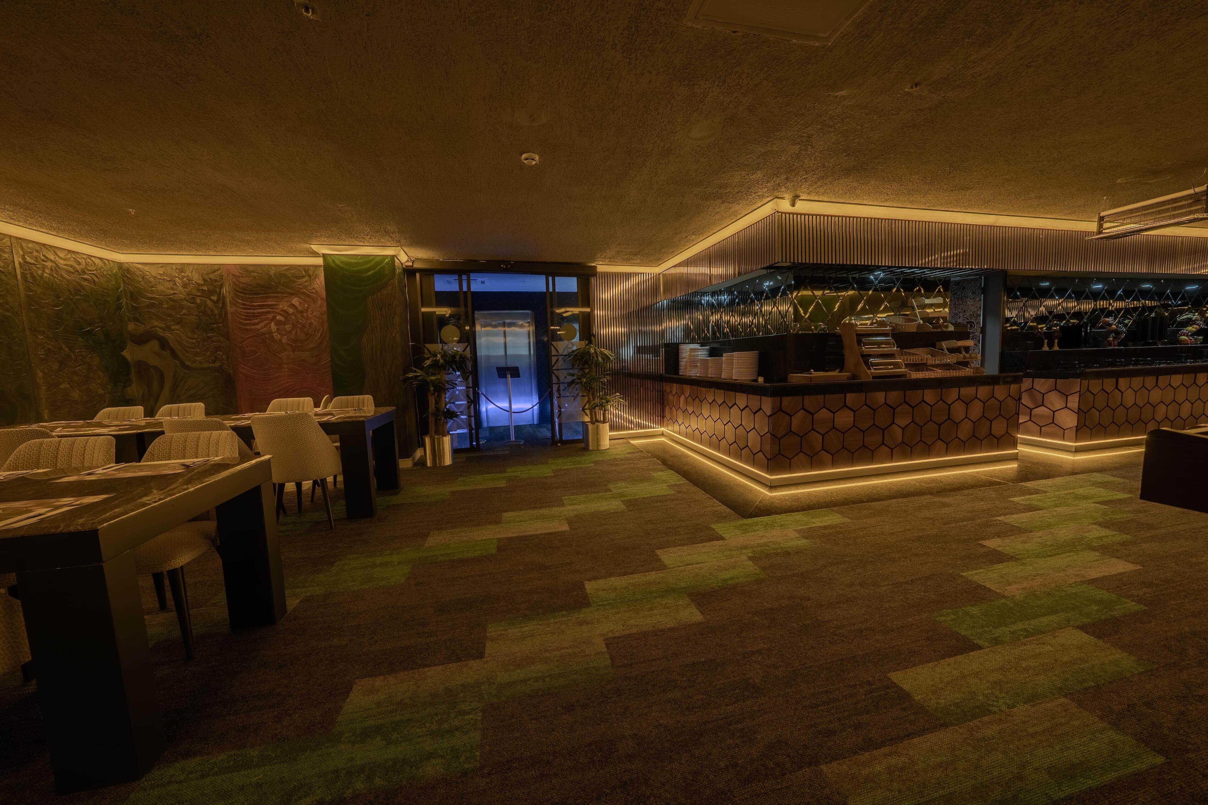 A bar area with a counter, seating, and a patterned carpet.