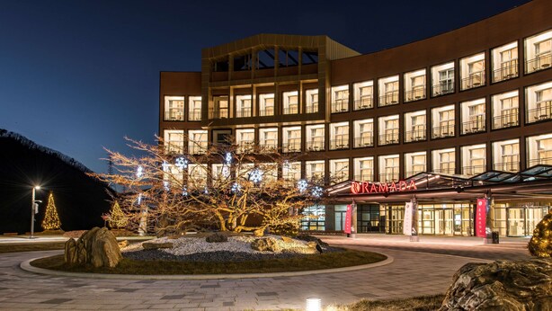 A modern hotel with a curved facade, multiple balconies, and a well-lit entrance. - Ramada Hotel & Suites by Wyndham Gangwon Pyeongchang (Pyeongchang)
