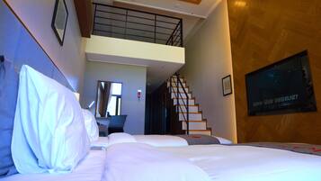 Una habitación de hotel con cama, televisión, escalera y una puerta que da a otra habitación.