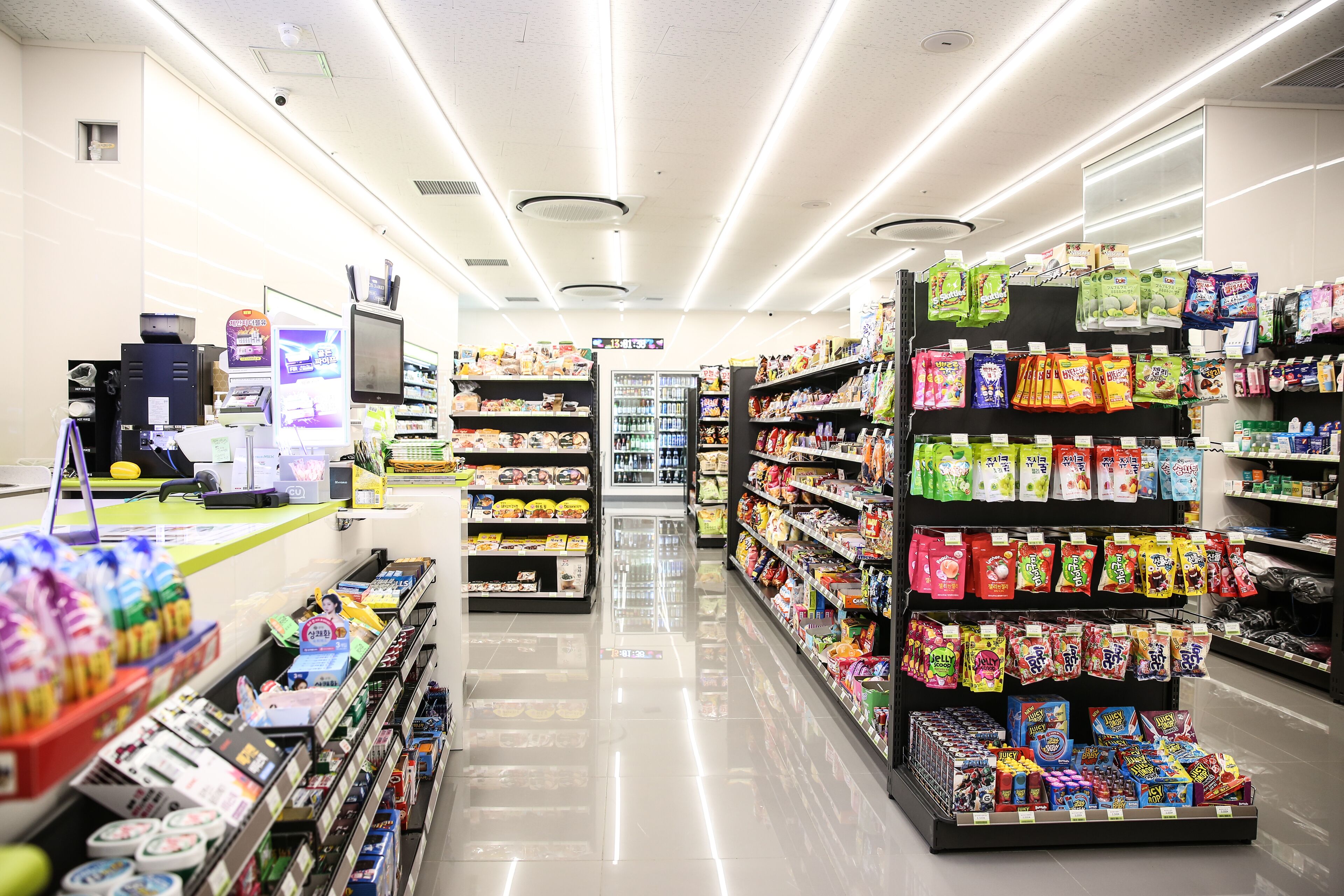A brightly lit supermarket aisle with shelves stocked with snacks and beverages.