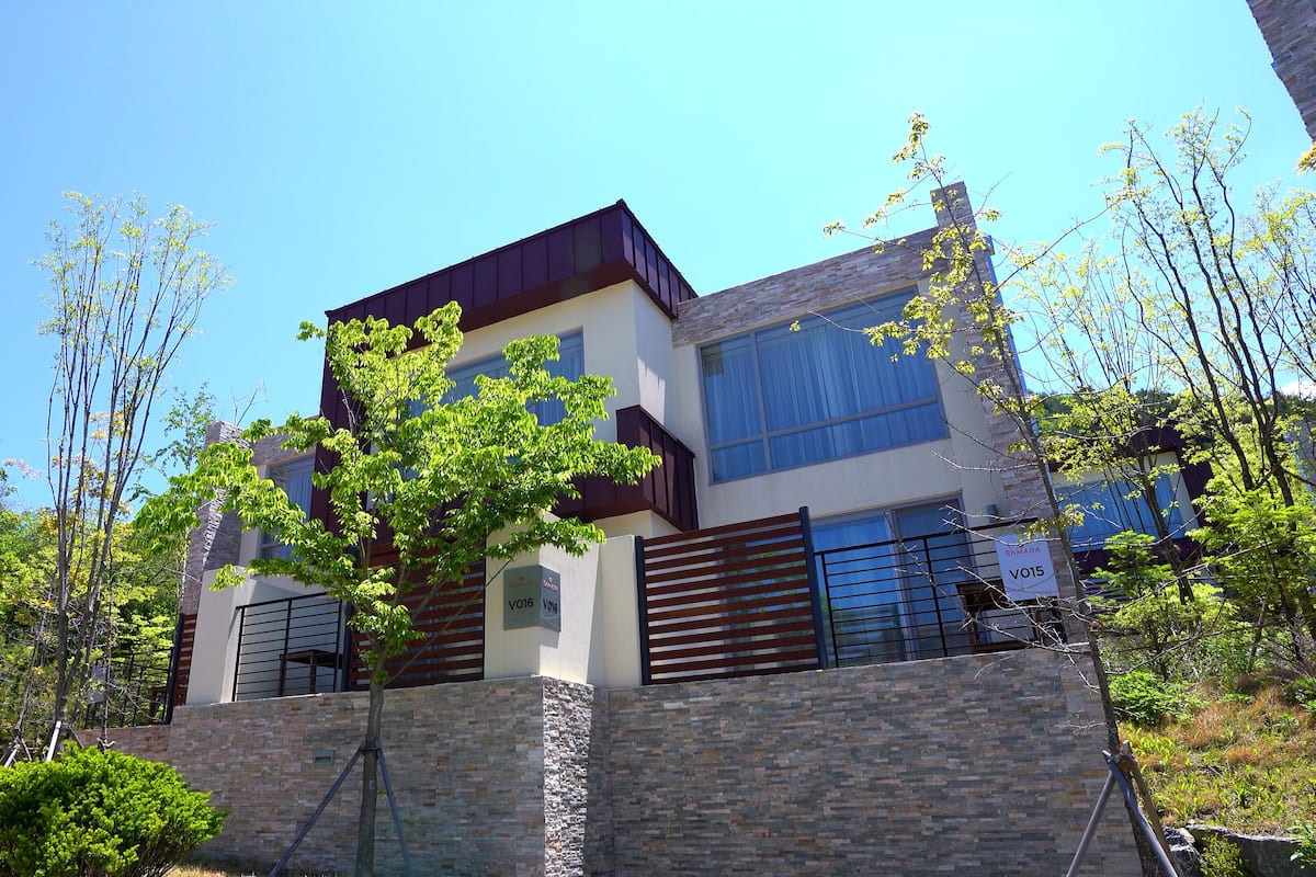 A modern two-story building with a stone facade and large windows.